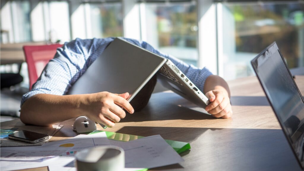 Man with laptop covering his head - bored at work