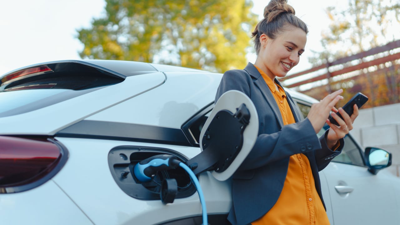 Happy woman charging an Electric Car at home
