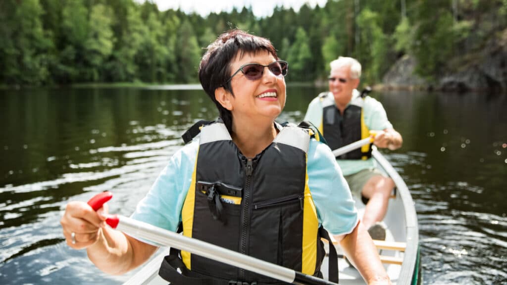 couple in life vests canoeing in forest lake