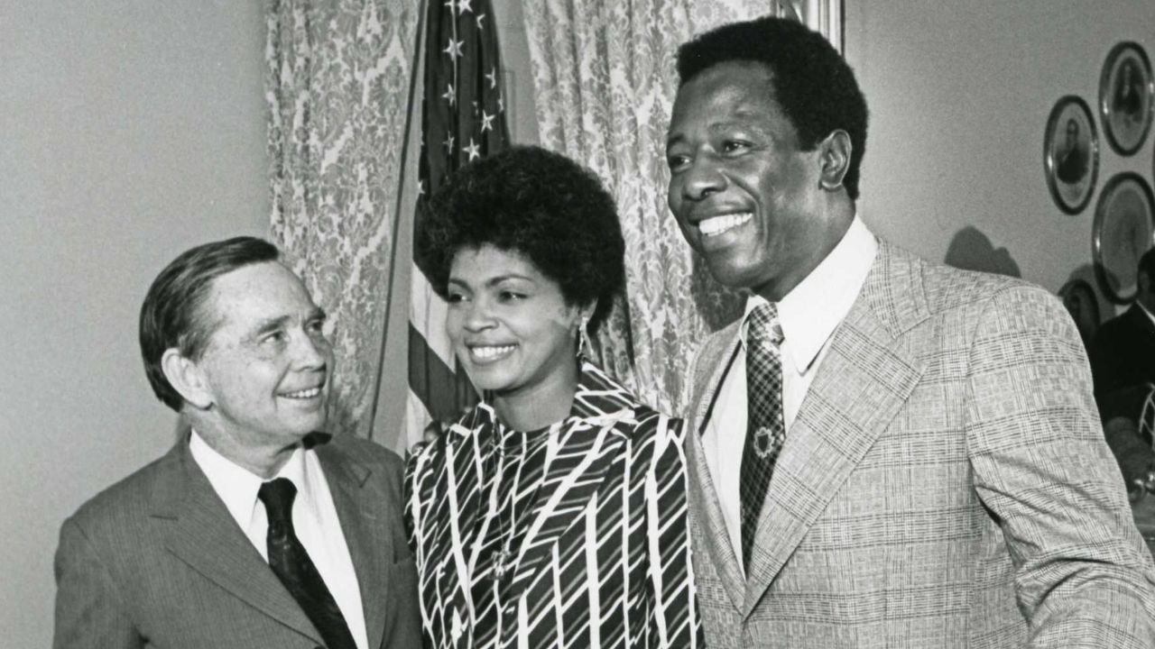 Black and white photograph print of Carl Albert shaking hands with Mrs. Aaron as Hank Aaron looks on. July 14, 1974.