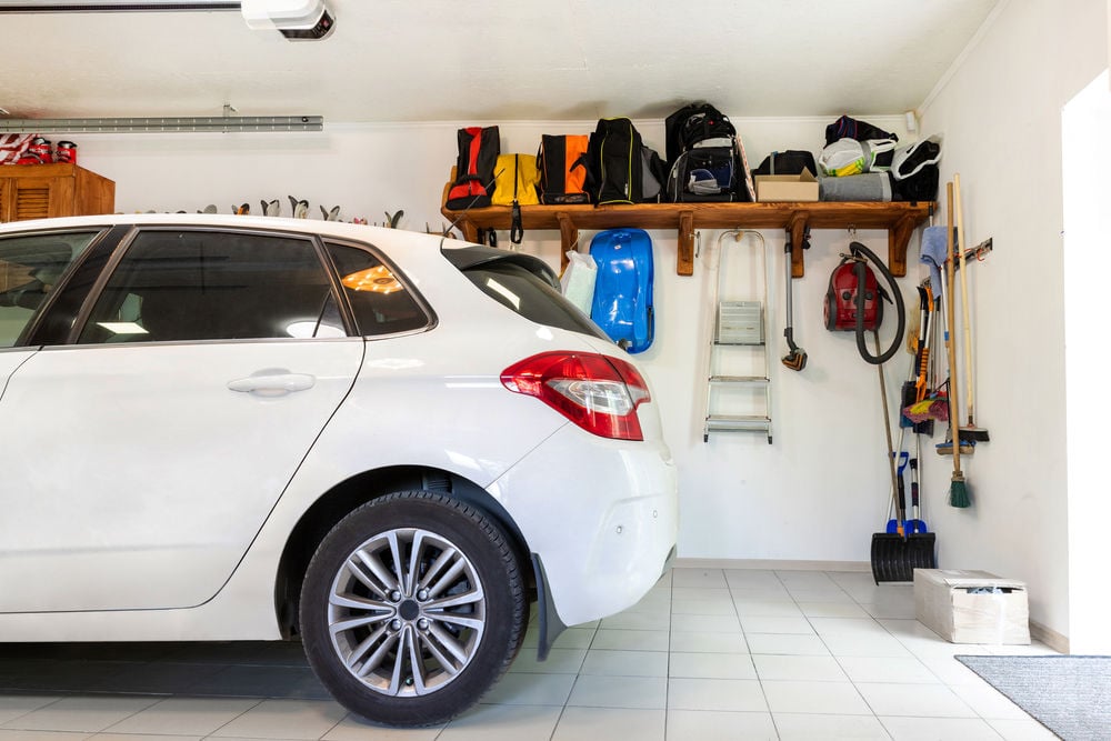 Home suburban car garage interior with wooden shelf , tools and equipment stuff storage warehouse on white wall indoors. Vehicle parked at house parking background