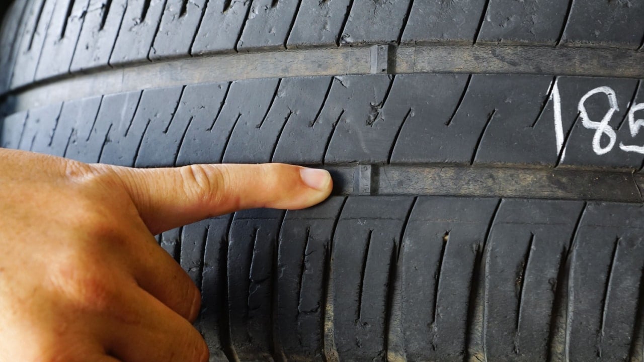 Finger pointing at tyre treadwear indicator / Tyre check and replacement for safety concept