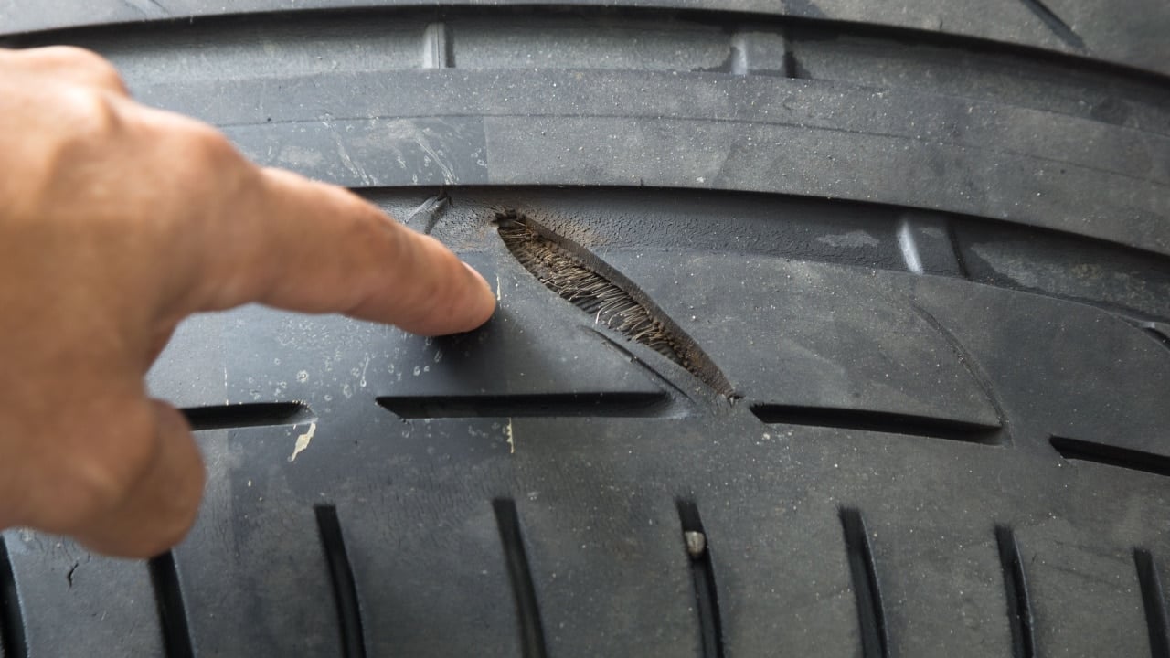 Selective focus of crack damage on tire tread with blurred finger pointing to damage on tire tread