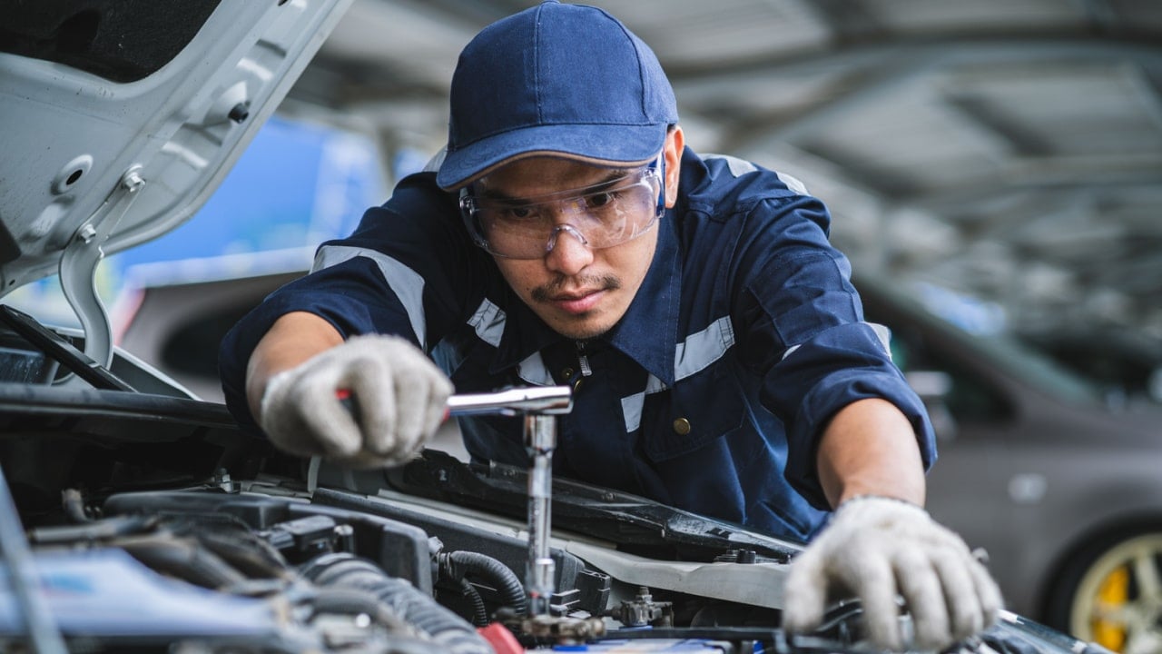 Portrait of an Asian mechanic checking the safety of a car. Maintenance of damaged parts in the garage. Maintenance repairs.