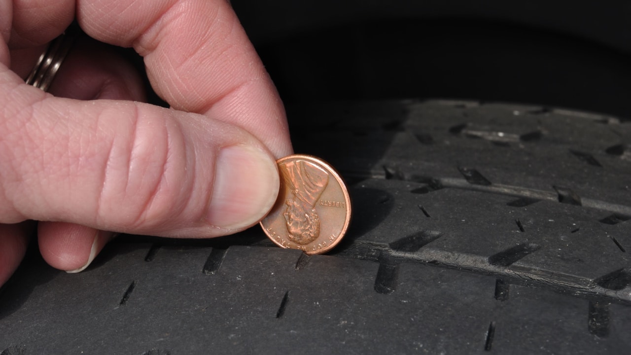 Inspecting The Wear Of A Balding Tire Tread Using a Penny