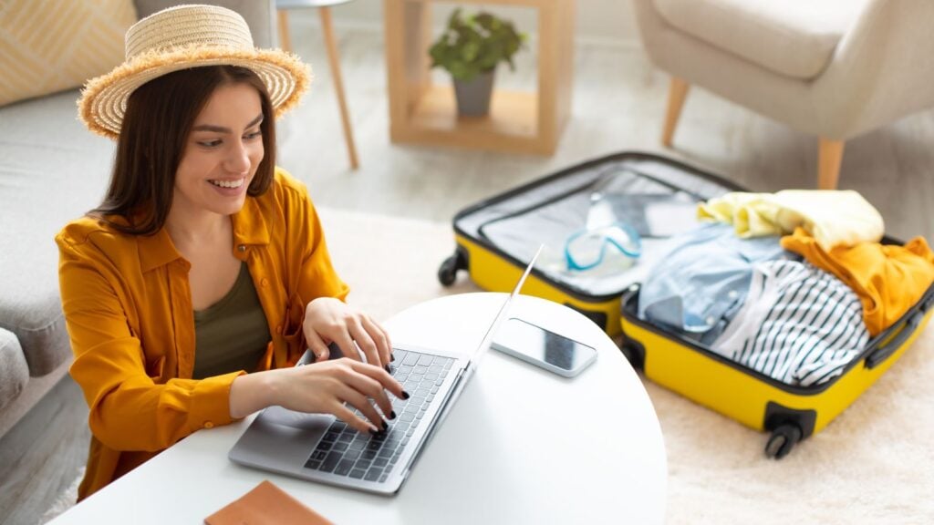 woman on computer travel suitcase