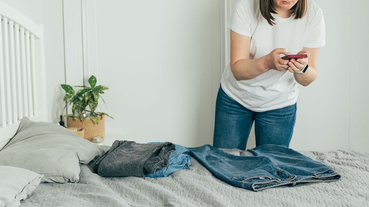 Woman taking pictures of pairs of jeans to sell online